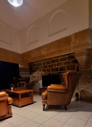 a living room with two chairs and a stone fireplace at L'écrin des petits bonheurs in Dole