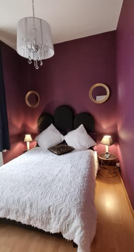 a bedroom with a large bed with purple walls at L'écrin des petits bonheurs in Dole