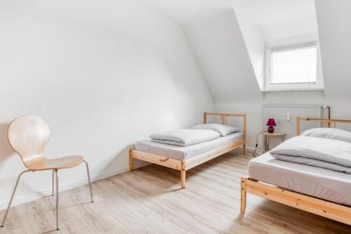 2 Betten in einem weißen Zimmer mit einem Stuhl in der Unterkunft Gutmensch Oberhausen 4 Schlafzimmer in Oberhausen