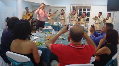 a group of people taking pictures of a man playing music at La Aurora Hotel Like Home in Huamantla
