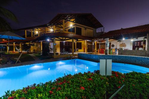 a swimming pool in front of a house at night at Pousada Paraíso do Vento in Cumbuco