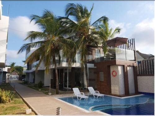 a house with palm trees and a swimming pool at Casa de Playa frente al mar. in Coveñas