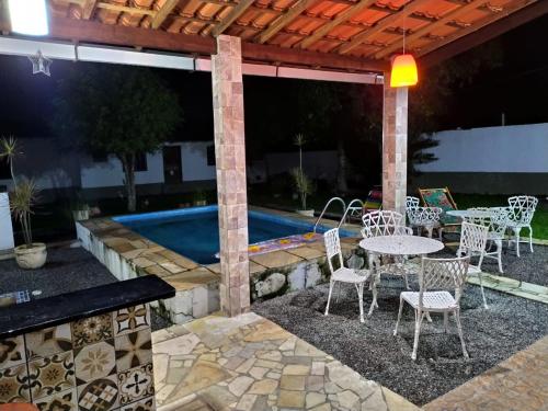 un patio con mesa, sillas y piscina en Casa Aconchegante Lazer e Descanso en Araruama