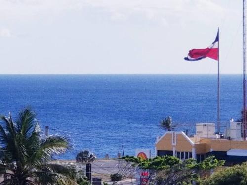 a flag on top of a building next to the ocean at Maravilloso Apto en Santo Domingo in Santo Domingo