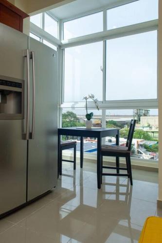 a kitchen with a table and a refrigerator and a window at Maravilloso Apto en Santo Domingo in Santo Domingo