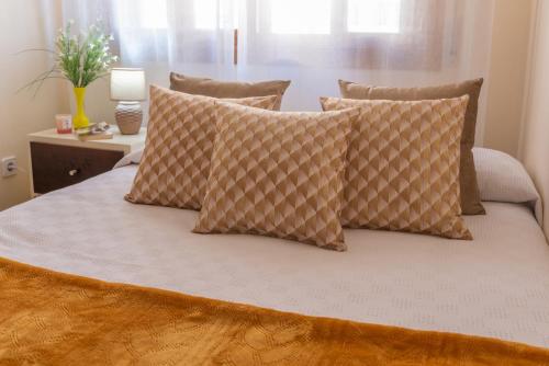 a bed with pillows on it in a room at apartamento centro sanxenxo con parking gratis in Sanxenxo