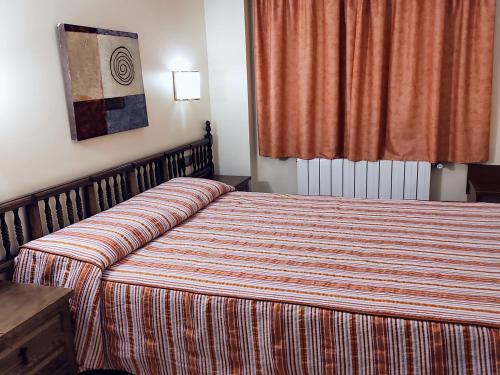 a hotel room with a bed with a striped blanket at HOTEL FESTA BRAVA in Andorra la Vella