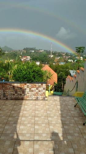 un arco iris en el cielo sobre una ciudad con un banco en Alta Vista, en Penedo