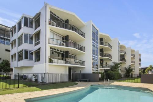 an apartment building with a swimming pool in front of it at Pumicestone Lodge Unit 12 26 Maloja Ave in Caloundra