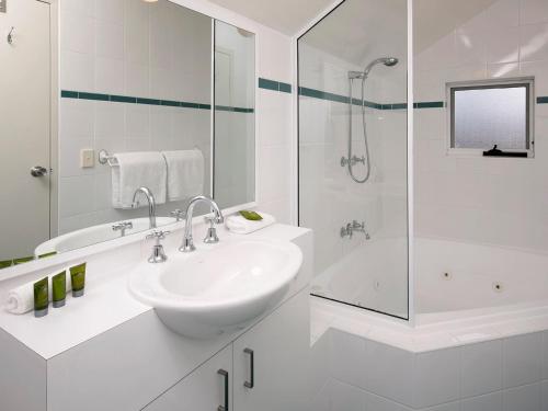 Un baño blanco con lavabo y ducha. en Cascades 18 3 Kurrajong Street, en Jindabyne