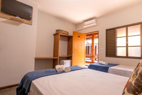 a room with two beds and a tv on the wall at Pousada Caminho das Aguas in Brotas