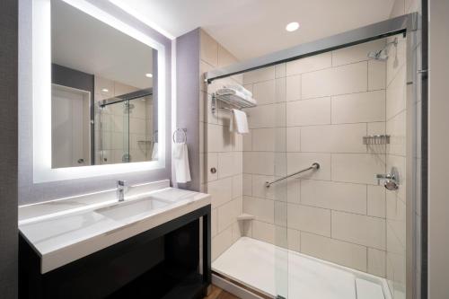 ロサンゼルスにあるHyatt House LAX Century Blvdの洗面台と鏡付きシャワーを備えたバスルーム