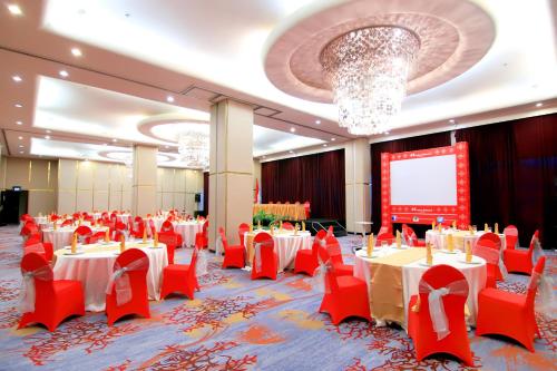 a banquet hall with red tables and chairs and a screen at Swiss-Belhotel Ambon in Ambon