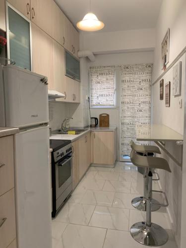 una cocina con electrodomésticos blancos y taburete. en 2 Bedrooms Apartment Center of Athens 4 min Subway, en Atenas