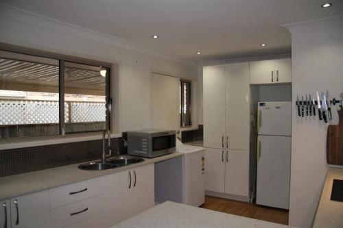 a kitchen with white cabinets and a sink and a refrigerator at Jarrah by Kingscliff Accommodation in Kingscliff
