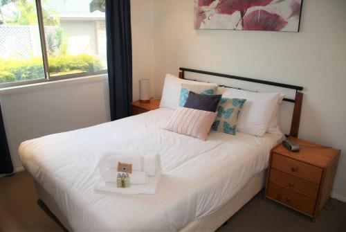a bedroom with a white bed with a box on it at Jarrah by Kingscliff Accommodation in Kingscliff
