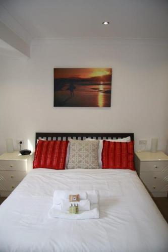 a bedroom with a white bed with red pillows at Jarrah by Kingscliff Accommodation in Kingscliff