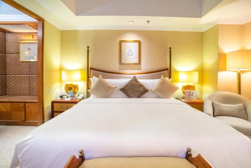 a bedroom with a large white bed and two chairs at Crowne Plaza Qingdao, an IHG Hotel in Qingdao