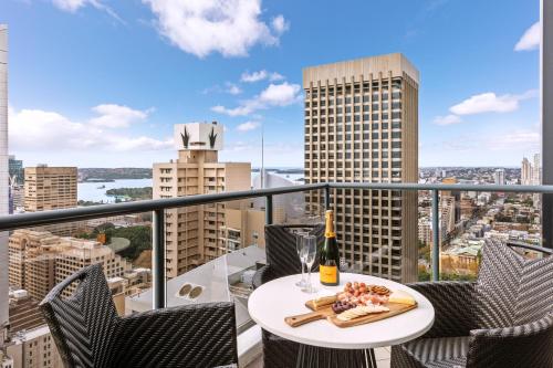 a table with a plate of food on top of a balcony at Meriton Suites Pitt Street, Sydney in Sydney
