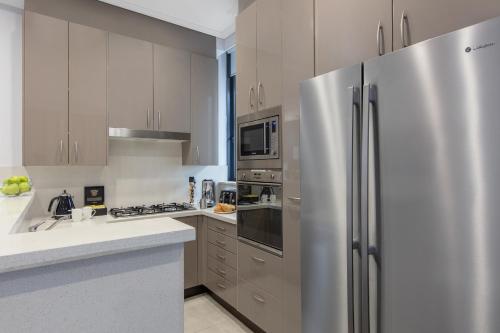 a kitchen with a stainless steel refrigerator at Meriton Suites Pitt Street, Sydney in Sydney