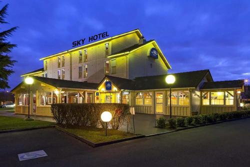 a large building with a sky hotel at night at Sky Hotel Goussainville Charles de Gaulle in Goussainville