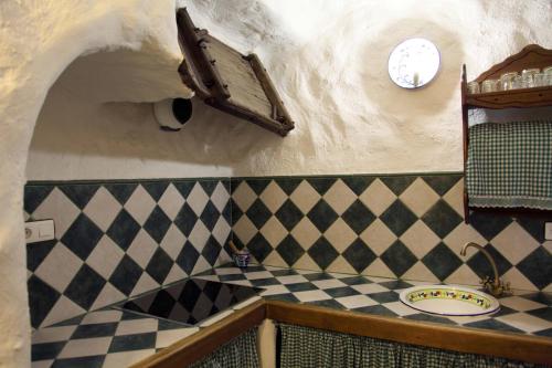 La salle de bains est pourvue d'un comptoir en damier et d'une horloge murale. dans l'établissement Cuevas La Atalaya, à Huéscar