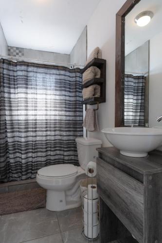 a bathroom with a toilet and a sink and a mirror at Collins Village Hotel Boutique in El Porvenir