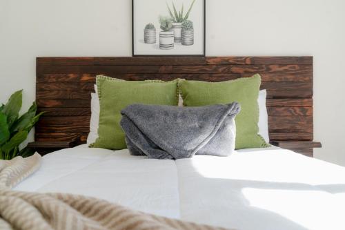 a white bed with green pillows and a wooden headboard at Collins Village Hotel Boutique in El Porvenir