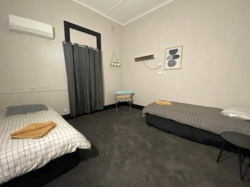 ein Zimmer mit 2 Betten und einem Stuhl darin in der Unterkunft Imperial Hotel Coonabarabran in Coonabarabran