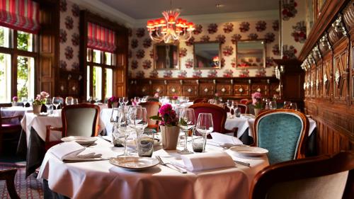 a dining room with white tables and chairs and a chandelier at South Lodge in Lower Beeding