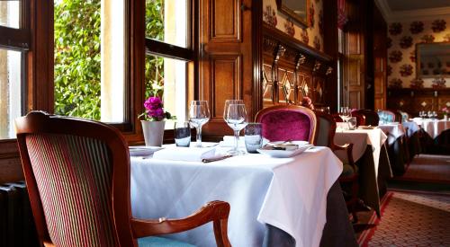 a row of tables in a restaurant with wine glasses at South Lodge in Lower Beeding