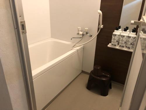 a bathroom with a tub and a toilet and bottles of water at Cool-inn Otaru in Otaru