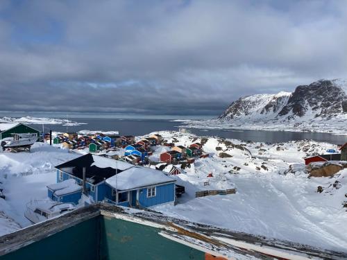 a village in the snow with a mountain in the background at Isi4u apartments, snowmobile and dogsled in Sisimiut