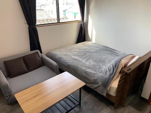 a small room with a bed and a couch at コンドミニアムホテル Stay inn Blue in Hukue