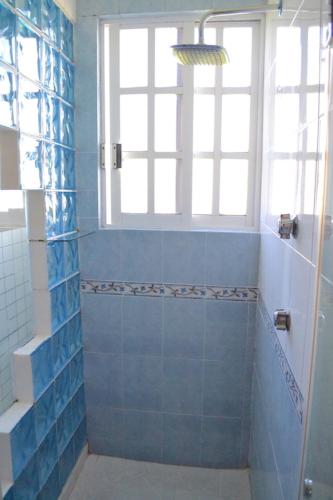 a bathroom with a shower with blue tiles and a window at La Aurora Hotel Like Home in Huamantla