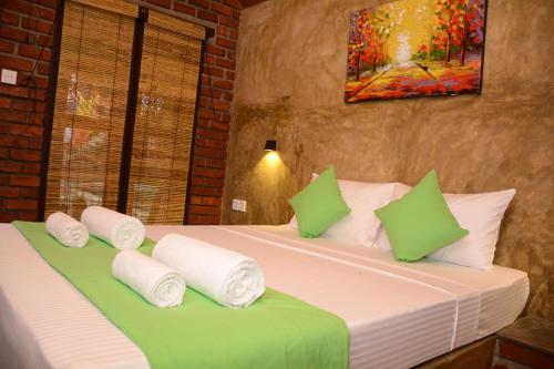 a bedroom with a bed with green and white pillows at Negombo The Nature Villa and Cabanas in Negombo