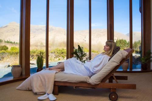 a woman sitting in a chair in a room with a window at Delphi Resort Hotel & Spa in Leenaun