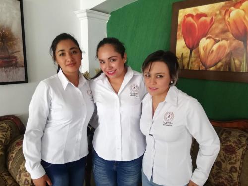 three women in white shirts posing for a picture at La Aurora Hotel Like Home in Huamantla