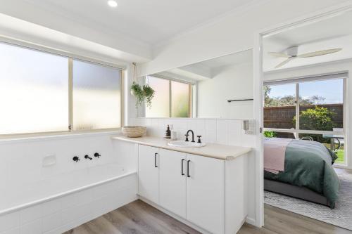 a white bathroom with a sink and a tub and a bed at 2 Bedroom Unit - Close To The Beach - Free Parking - Free WIFI in Ocean Grove