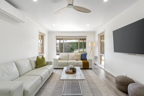 a living room with a white couch and a flat screen tv at 2 Bedroom Unit - Close To The Beach - Free Parking - Free WIFI in Ocean Grove