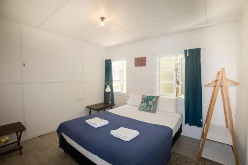 1 dormitorio con 1 cama con 2 toallas en Cabana - Original Straddie Beach Shack, en Point Lookout