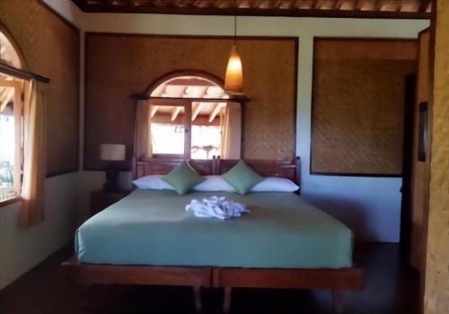 a bedroom with a white bed with a window at Bali Mountain Retreat in Selemadeg