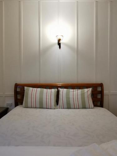 a bed with a pillow and a light on the wall at TAVEE Guesthouse in Bangkok