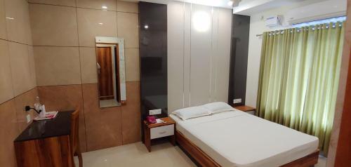 1 dormitorio con cama blanca y espejo en Sree Gokulam Sabari en Guruvāyūr