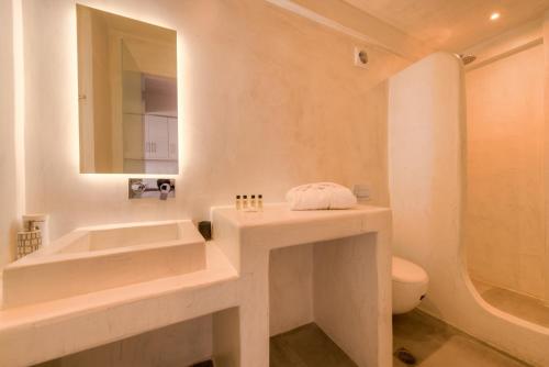 a bathroom with a sink and a toilet and a mirror at The Muses of Santorini Private Jacuzzi Suites in Vóthon