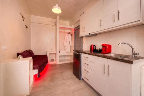 a kitchen with white cabinets and a sink and a stove at The Muses of Santorini Private Jacuzzi Suites in Vóthon