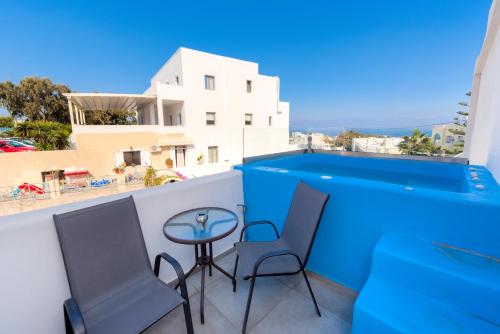 a balcony with two chairs and a table with a view at The Muses of Santorini Private Jacuzzi Suites in Vóthon