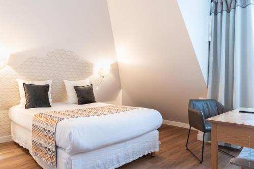 a bedroom with a bed and a desk and a table and chair at Hôtel Versailles Chantiers in Versailles