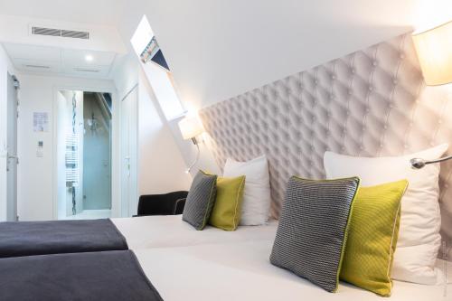 a bedroom with a large bed with yellow pillows at Hôtel Versailles Chantiers in Versailles