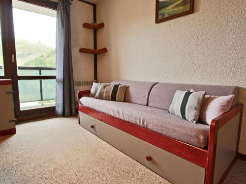 - un canapé avec des oreillers dans une chambre avec une fenêtre dans l'établissement Studio Chamrousse, 1 pièce, 4 personnes - FR-1-340-146, à Chamrousse